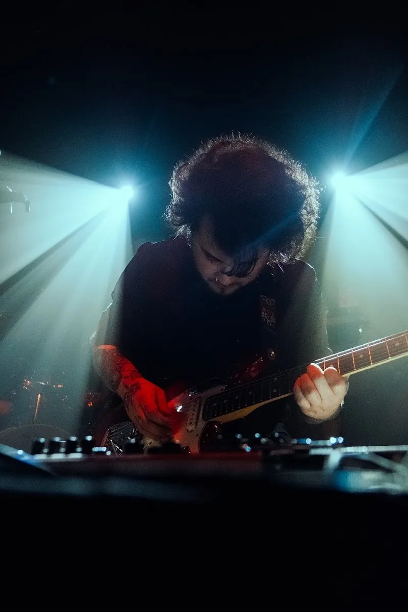 Dr Verdugo tocando guitarra entre focos de luz